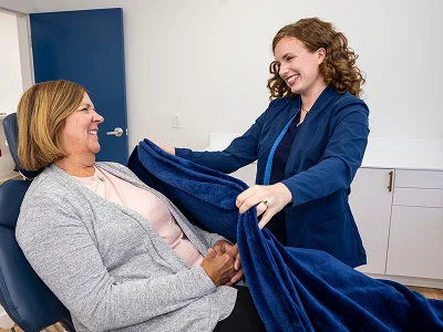 Team member tucking a soft blanket around a smiling patient